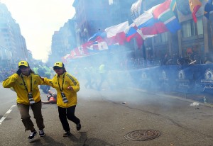 People react to an explosion at the 2013 Boston Marathon in Boston, Monday, April 15, 2013. Two explosions shattered the euphoria of the Boston Marathon finish line on Monday, sending authorities out on the course to carry off the injured while the stragglers were rerouted away from the smoking site of the blasts. (AP Photo/The Boston Globe,  John Tlumacki)