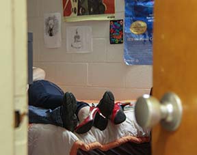 Photo illustration by Lori Allen//The News / Two students are shown in a bed in a residential college. Many students are upset by a new visitor policy, which prohibits students from having overnight visitors during the week.
