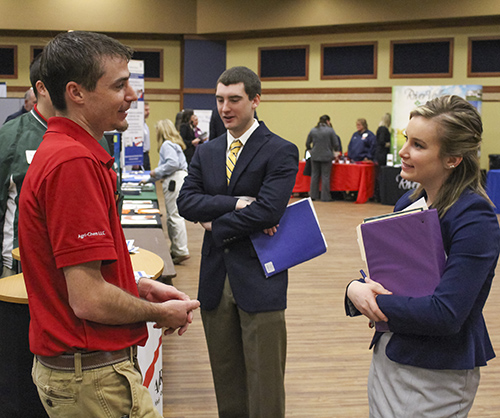 Nicole Ely/The News Tori Heddinger, junior from Mariah Hill, Ind., and Austin Reed, junior from Monticello, Ill., speak with agricultural company representatives.