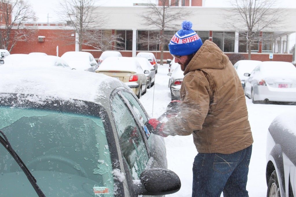 Thomas Whited, graduate student from Kansas City, Mo., removes ice and snow from his car during February's snowstorm.