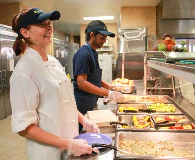 Jenny Rohl/The News Mary Jo Payton, a staff worker at Winslow Dining Hall happily helped to serve  peach-galzed bison meatloaf and sweet potato gratin at the Harvest Dinner.