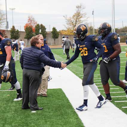 Nicole Ely/The News President Bob Davies shakes the hand of sophomore running back Demetric Johnson as he runs off the field after the game against Eastern Illinois Saturday. 